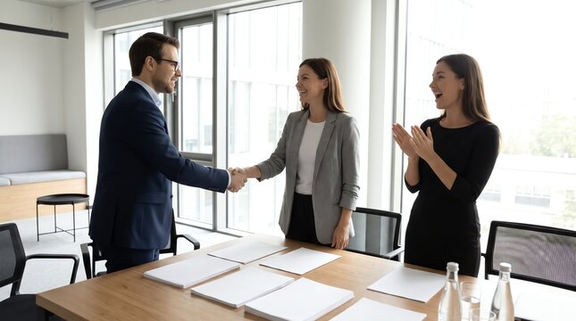 Successful business agreement is finalized with a handshake and applause in a modern office setting