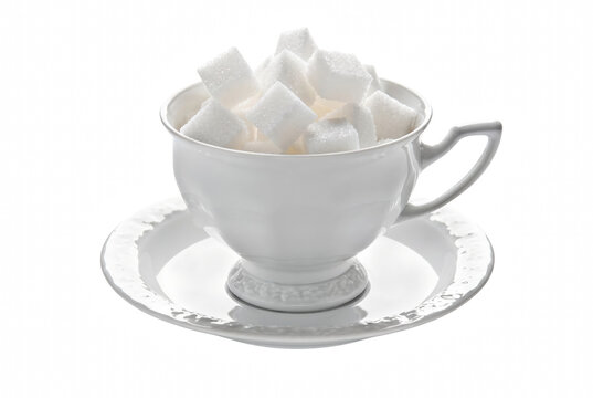 White teacup overflowing with sugar cubes