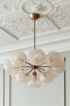 Brass multi-arm pendant chandelier with glass globes hanging from a decorative ceiling in a modern interior space, showcasing elegant design and craftsmanship