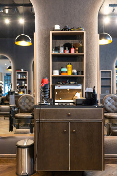Dark wood styling station is showcasing open shelves, bottles, coiled hairdryer, towels at salon