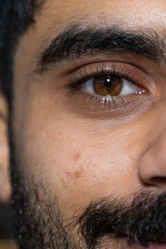 African man gazing toward camera in close-up, revealing brown eye, eyebrow, eyelashes, stubble