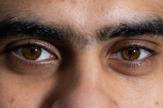 Adult male looking directly toward camera in studio, showing brown irises and skin texture