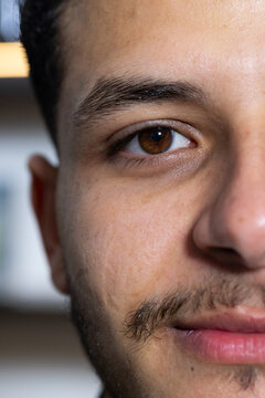 African man gazing toward camera in studio with blurred shelf, showing brown eye, warm light band