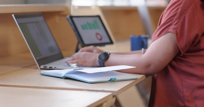 Woman placing pen, sorting paper, typing on laptop, tapping tablet charts for report, copy space