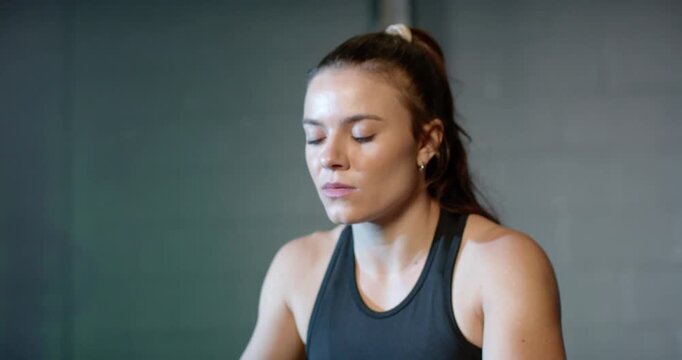 Woman wearing black tank and watch breathing in then pulling rower handle for strength at gym