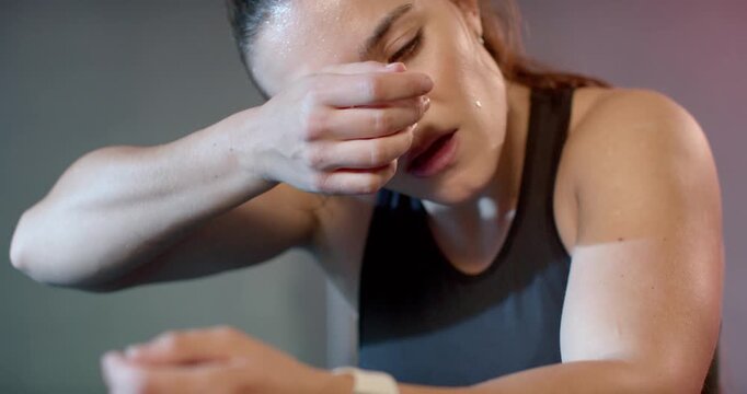 Heavy workout driving woman in black top leaning, wiping sweat, checking smartwatch near gym rings