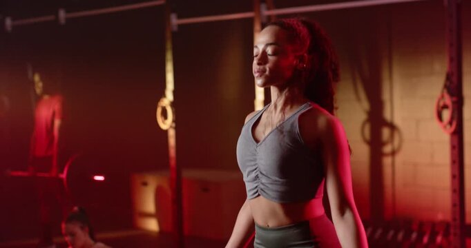 After rope swing, African American woman jumping rope in grey top, leggings, warming up at gym