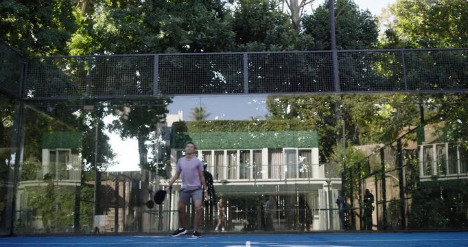 Diverse male duo in tees using paddles on blue court, green player entering left sparking volleys