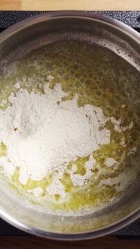 Flour added to melted butter starts sauce cooking in saucepan. Sauce thickens slowly as flour blends into warm melted butter. Sauce cooking shapes flavor for hearty dinner meal.