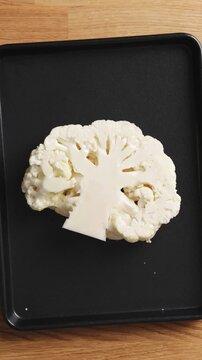 Olive oil brushed onto cauliflower steak before roasting begins. Cauliflower steak offers healthy alternative to traditional meat dish. Cauliflower recipe fits simple vegetarian dinner meal.