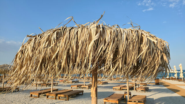 Thatch beach umbrella and sun loungers on a sandy beach