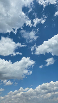 White cumulus clouds floating in a vibrant blue summer sky