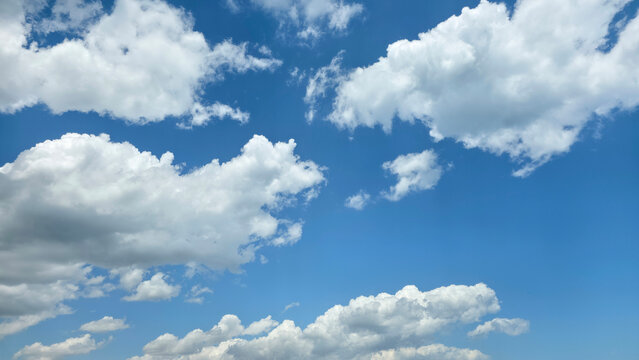 White cumulus clouds floating in a clear blue summer sky