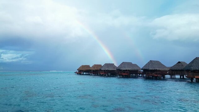 Overwater bungalows with a double rainbow in tropical paradise. Moorea island, french polinesia