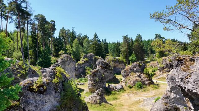 Luftaufnahme des Felsenmeers im Wental mit markanten Felsformationen aus Jurakalk, umgeben von einem dichten Nadelwald und Wanderwegen auf der Schw&auml;bischen Alb bei Sonnenschein.