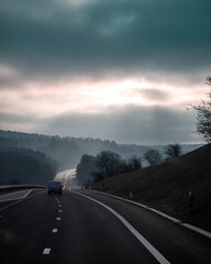 Autostrada na wzniesieniu z widokiem na słońce wychodzące zza chmur © Adam
