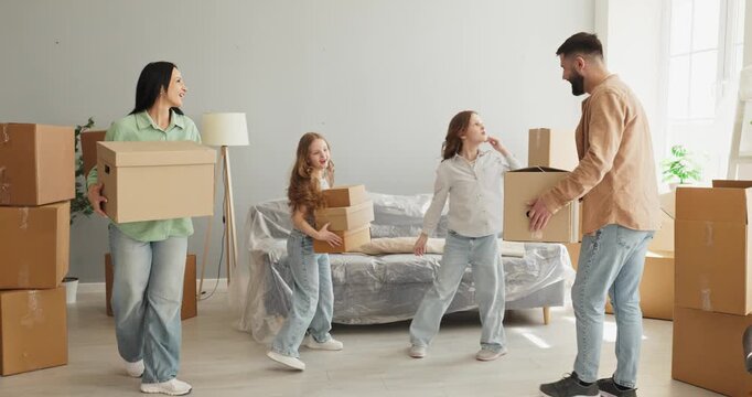 Family parents children moving boxes with happiness. In a bright home teamwork shines as unpacking starts around a wrapped sofa and stacked boxes. Clear concept of family relocation.