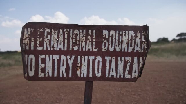 No entry to Tanzania international boundary signage at Kenya border between Maasai Mara national park reserve and Serengeti wildlife tourist area for crossing on foot