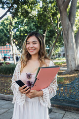 Fototapeta premium portrait of young latina woman holding folders in public park in Mexico Latin America