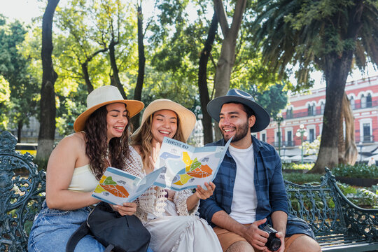 portrait of young latin friends traveling holding a tourist map in Mexico Latin America, hispanic people tourist in colonial city 