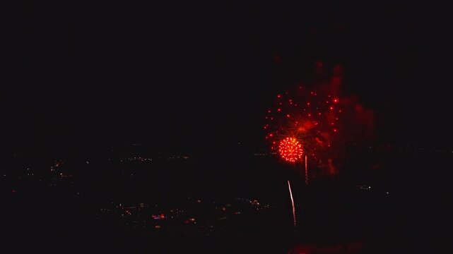 Fireworks burst brightly in the night sky above the city. The colorful displays mark the highlight of the annual festival. People gather to enjoy the show and celebrate together.