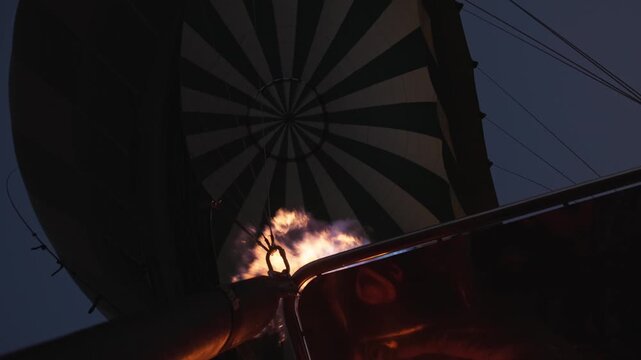 Slow motion in early morning darkness of hot air balloon fire, chemicals, liquid propane gas, and air rising as balloons rise for dusk ride through the sky on tourist adventure as flames shoot up 4k