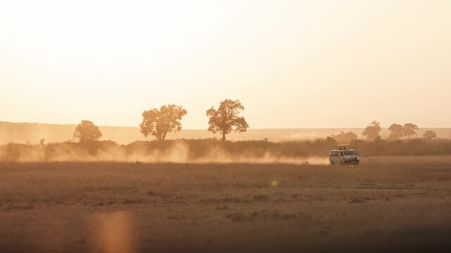 Early morning sunrise in African, Kenya landscape as off-road safari tour tourist trucks rush into Maasai Mara national park in Africa with tourists to view animal wildlife in slow motion nature 4k