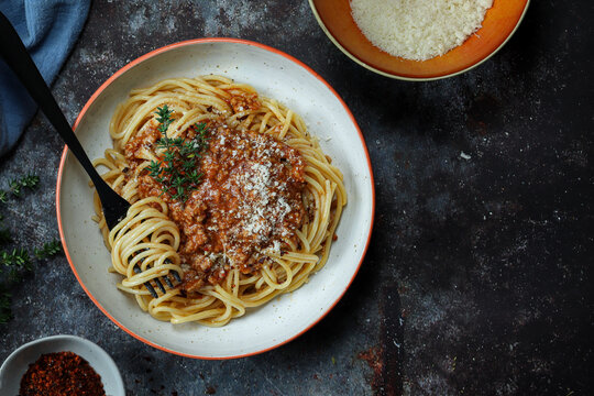 Spaghetti Bolognese mit geriebenem Parmesan - Rustikale Draufsicht in farbigen Seinguttellern