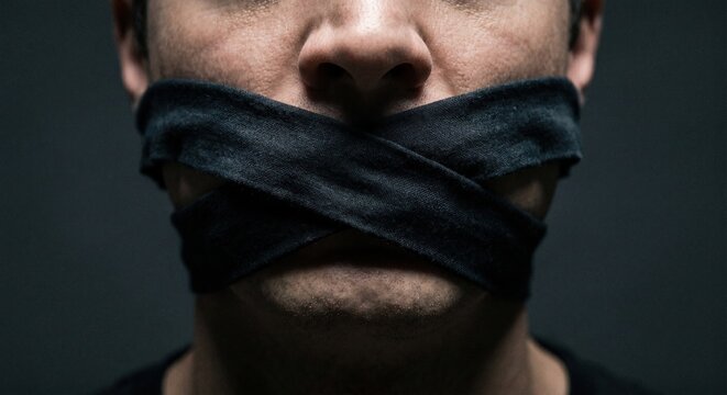 Man with his mouth gagged with cloth representing censorship, silence, and the restriction of free speech in a conceptual close-up portrait