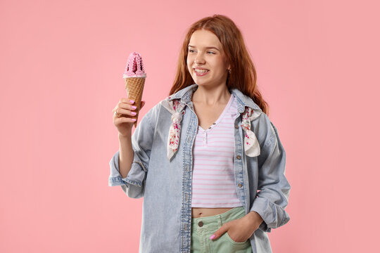 Happy teenage girl with delicious ice cream in waffle cone on pink background