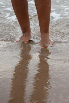 Close up of woman's feet in gentle ocean waves on beach