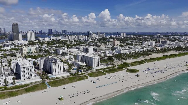 Aerial view of gentle waves rolling onto Miami Beach shore with people and surfers. c.