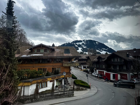 Switzerland - 11.03.2026. High-angle landscape shot taken from the GoldenPass Express train traveling between Montreux and Interlaken, looking down onto a winding mountain village road lined with clas