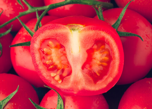 Red tomato cut on tomatoes background close up