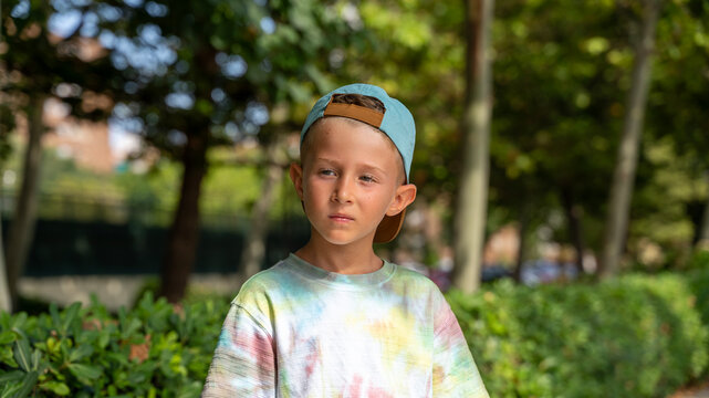 Thoughtful Young Boy Wearing Backward Cap in Sunny Park Portrait