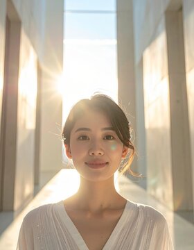 Portrait of a young woman standing in a bright modern architectural corridor with natural sunlight