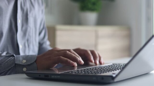 Businessman working and typing on laptop keyboard. Man hands scroll and swipe on laptop touchpad. Freelancer hand swiping laptop touchpad in sunshine remote workplace at home office.