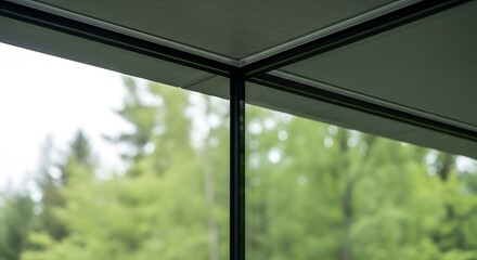 Fototapeta premium Modern architectural corner window frame looking out onto a lush green forest background.