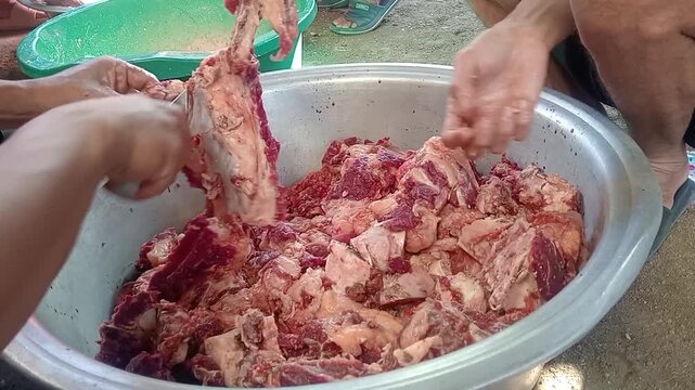 Preparing and sorting fresh raw meat in a large bowl for traditional cooking
