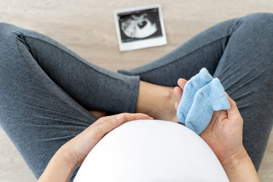 pregnant woman with baby shoes. pregnant woman, Mother gently touches the baby on stomach. Happy, family, growth, pregnancy, enjoyment , prepare newborn, take care, healthcare, tummy.