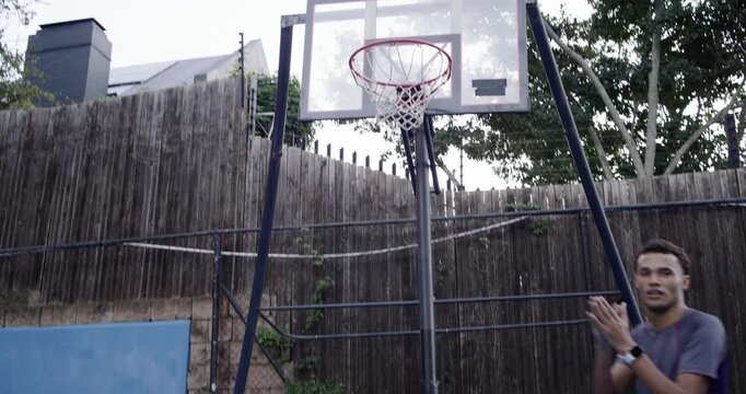 Diverse men gathering, gray tee signaling, contesting rebound under portable hoop, trying to score