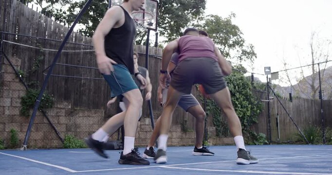 Four men maroon-shirt man dribbling low on backyard blue court drawing defense and driving to score