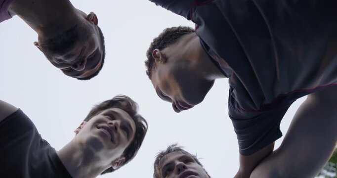After pep talk, Diverse male team leaning in, stacking hands showing watch, pressing, starting play