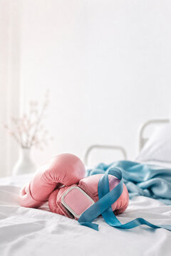 Pink Boxing Gloves with a Cancer Ribbon on a Hospital Bed