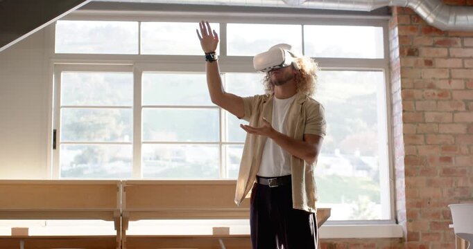 Man wearing VR set prepping controls rotating wrists reaching selecting objects in loft studio