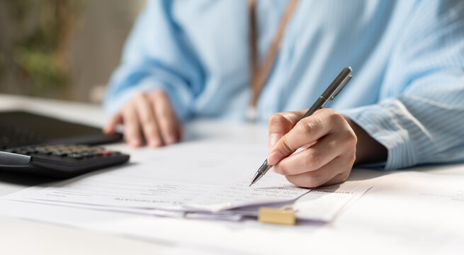 Businesswoman reviewing financial documents, tax paperwork, file folders, and business records on a laptop, representing accounting, document management, compliance, and office administration.