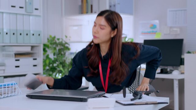 Businesswoman office lanyard badge at desk with computer folder plant scanner workplace, headset laptop support worker showing fatigue and stress during workday