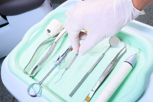 Dentist selecting dental instruments from sterile tray before dental procedure in modern clinic