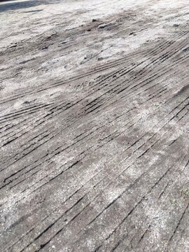 工事車両のタイヤ跡のある春の雨上がりの公園の砂利庭風景