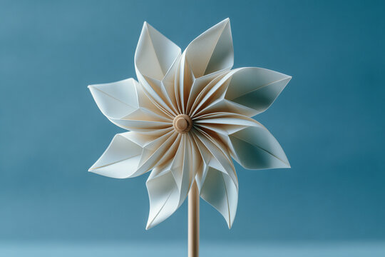 Origami paper windmill turbine against a clear sky minimal conceptual still life on pastel background